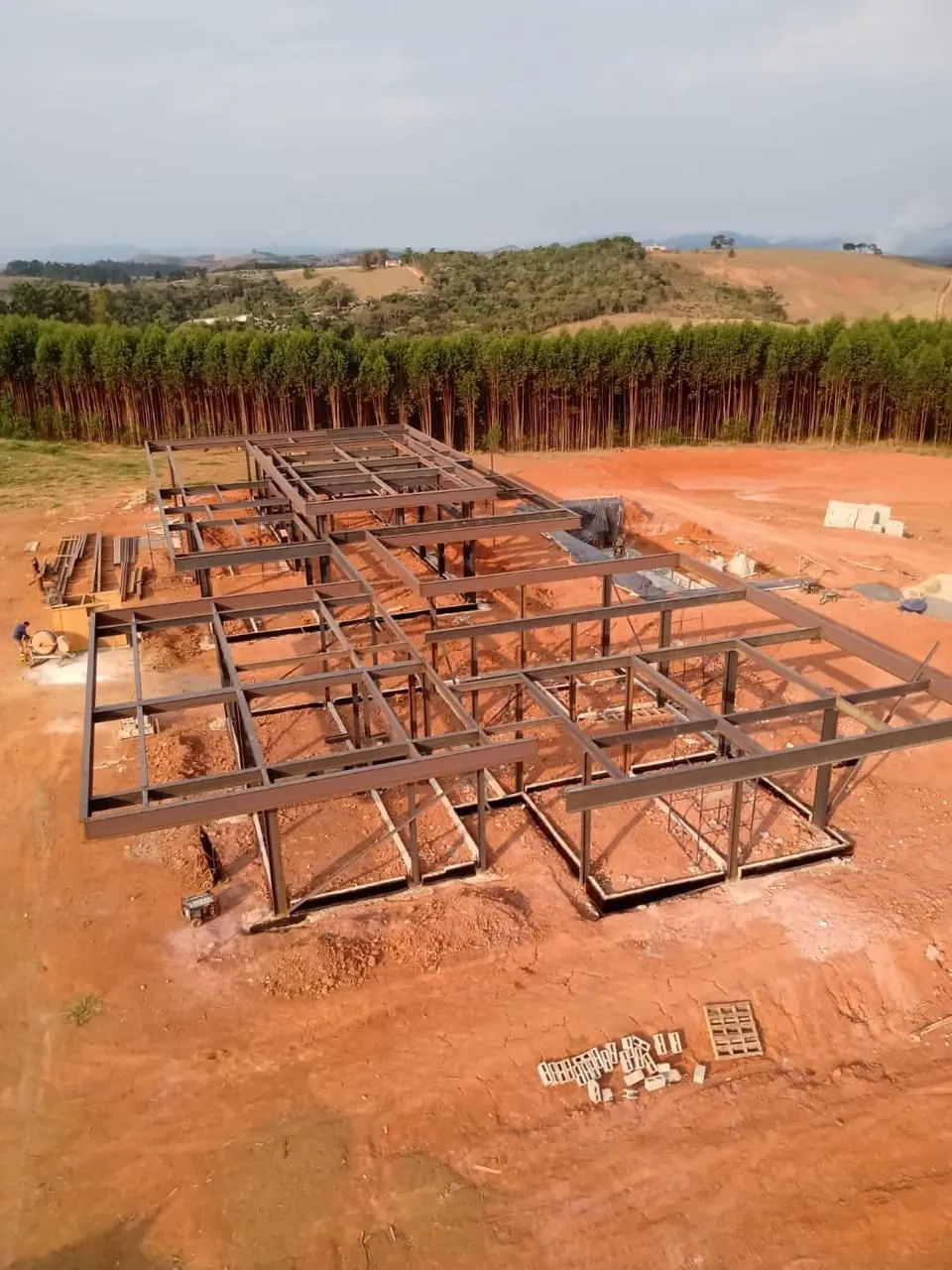 Estrutura em perfis metálicos em terreno aberto, cercada por eucaliptos