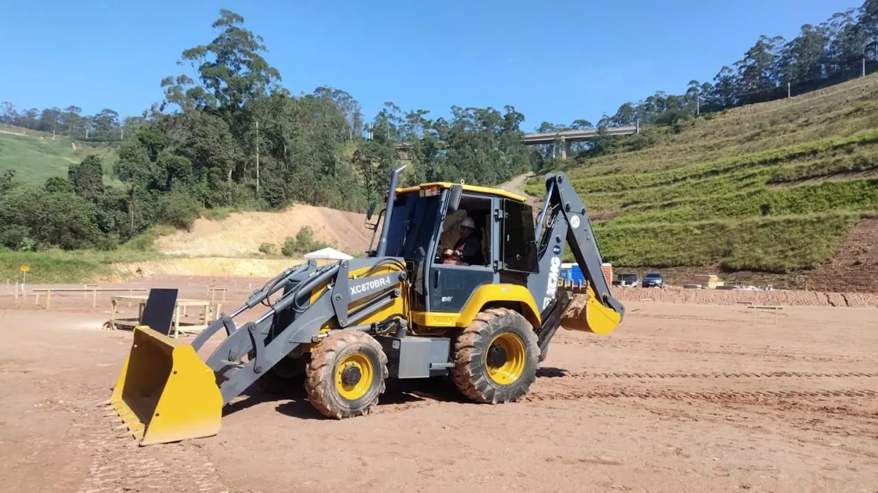 Retroescavadeira nivelando terreno em área de obra